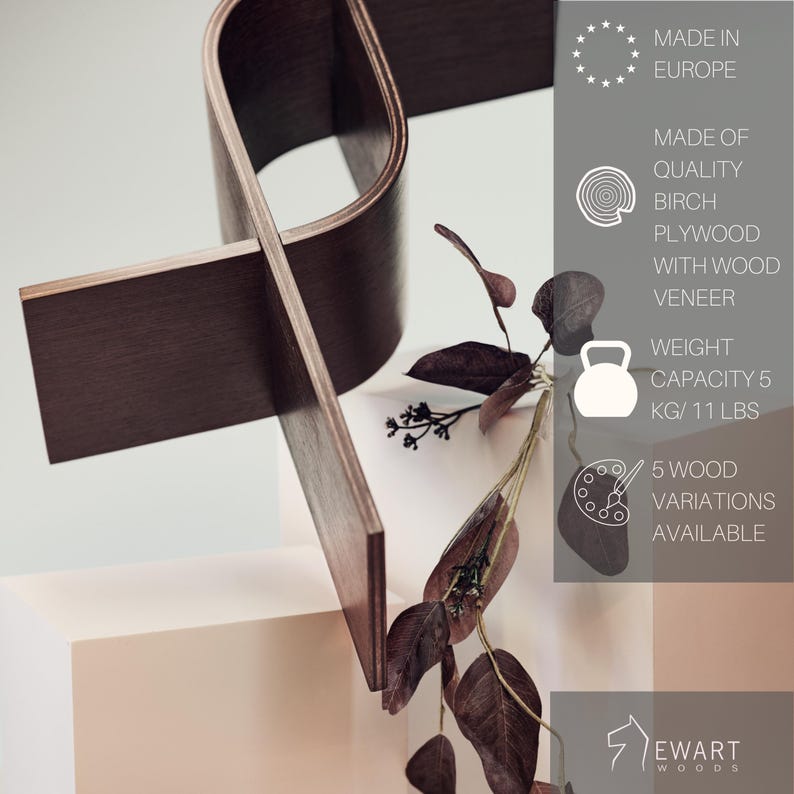 May include: A modern, dark brown wooden sculpture with a unique, intersecting design. The sculpture is made of birch plywood with wood veneer and has a weight capacity of 11 lbs. The image also includes text that says "Made in Europe."