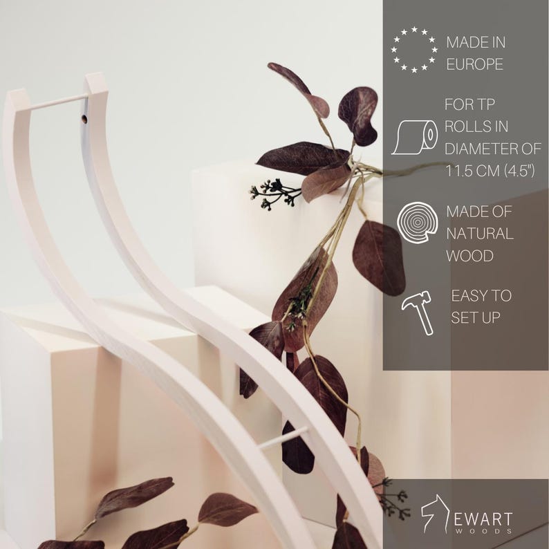 May include: A white curved wooden toilet paper holder with a minimalist design. The text on the image indicates it is made in Europe from natural wood, is easy to set up, and fits toilet paper rolls with a diameter of 11.5 cm or 4.5 inches.