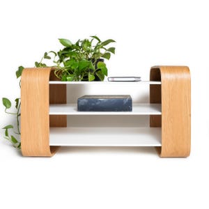 Peut inclure: Étagère moderne à trois niveaux avec une structure en bois clair et des étagères blanches. Les côtés incurvés du cadre ajoutent un élément de design unique. Une plante en pot et un objet rectangulaire foncé reposent sur les étagères. Idéale pour l'exposition ou le rangement.