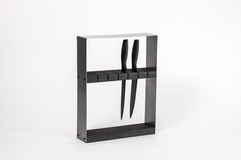 A sleek, modern knife block featuring a black metal frame and dark wooden insert, holding black-handled knives in evenly spaced horizontal slots.