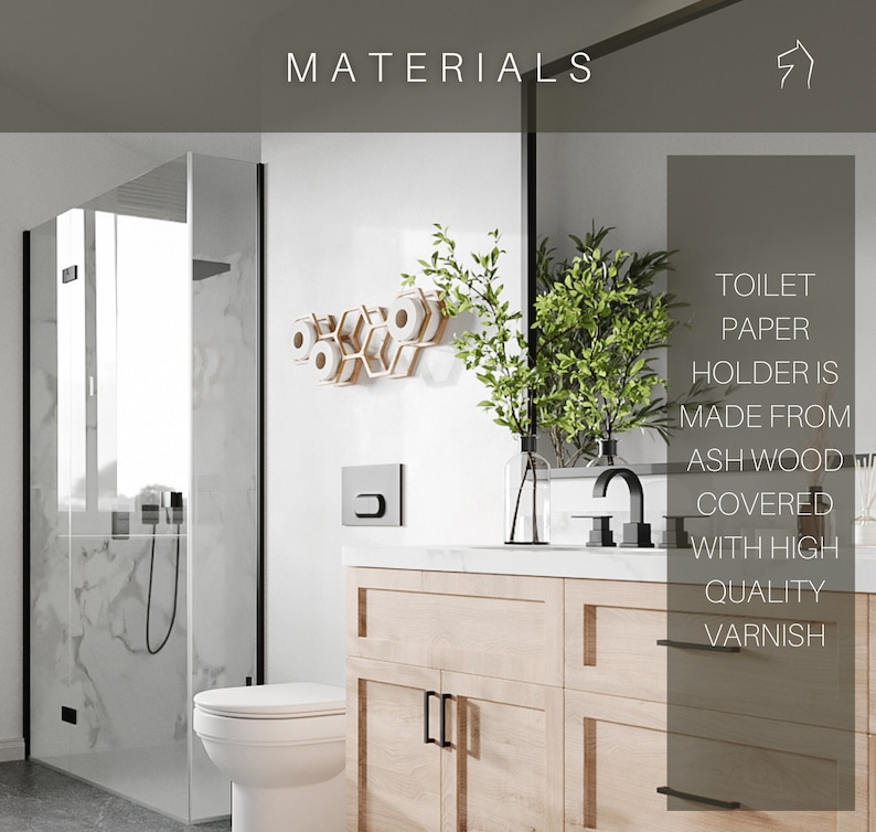 May include: A light-colored wooden toilet paper holder with a hexagonal honeycomb design mounted on a white wall. The text on the image states: MATERIALS. TOILET PAPER HOLDER IS MADE FROM ASH WOOD COVERED WITH HIGH QUALITY VARNISH.