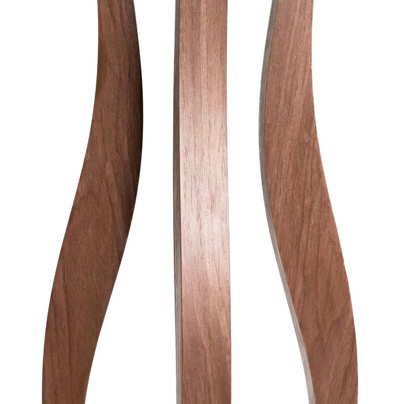 Detail shot of 3 curved walnut pillar legs of a tall indoor plant stand. Smooth hourglass shape, warm brown natural wood grain. Each leg approx. 2cm wide. Handmade birch plywood with walnut veneer finish. Unique sculptural flower pot stand.