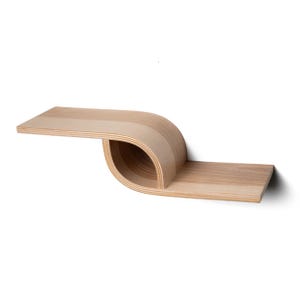 Pu&ograve; includere: Una moderna mensola da parete in legno chiaro con un design curvo unico. La mensola presenta una sezione piatta e rettangolare che si estende verso l'esterno, trasformandosi in una sezione curva e aperta, per poi tornare a una sezione piatta. La venatura del legno &egrave; visibile.