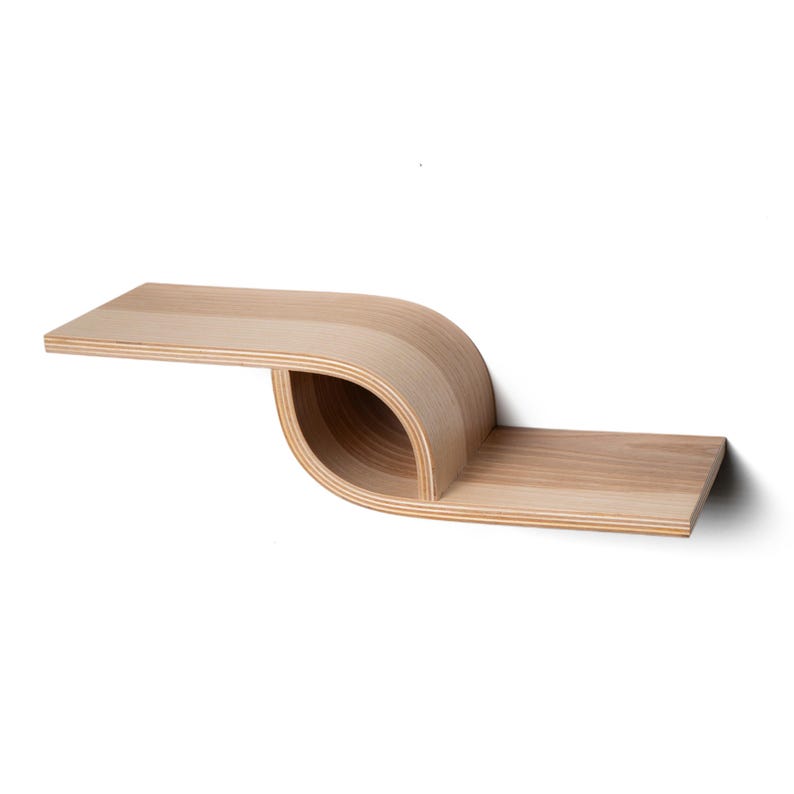 Pu&ograve; includere: Una moderna mensola da parete in legno chiaro con un design curvo unico. La mensola presenta una sezione piatta e rettangolare che si estende verso l'esterno, trasformandosi in una sezione curva e aperta, per poi tornare a una sezione piatta. La venatura del legno &egrave; visibile.