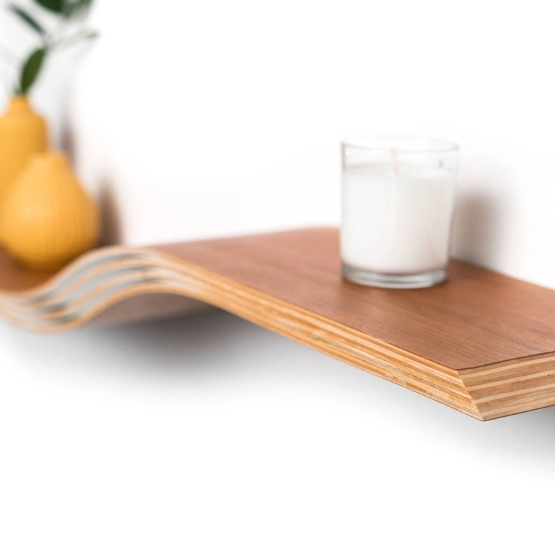 floating wall shelf closeup with white candle on top of it