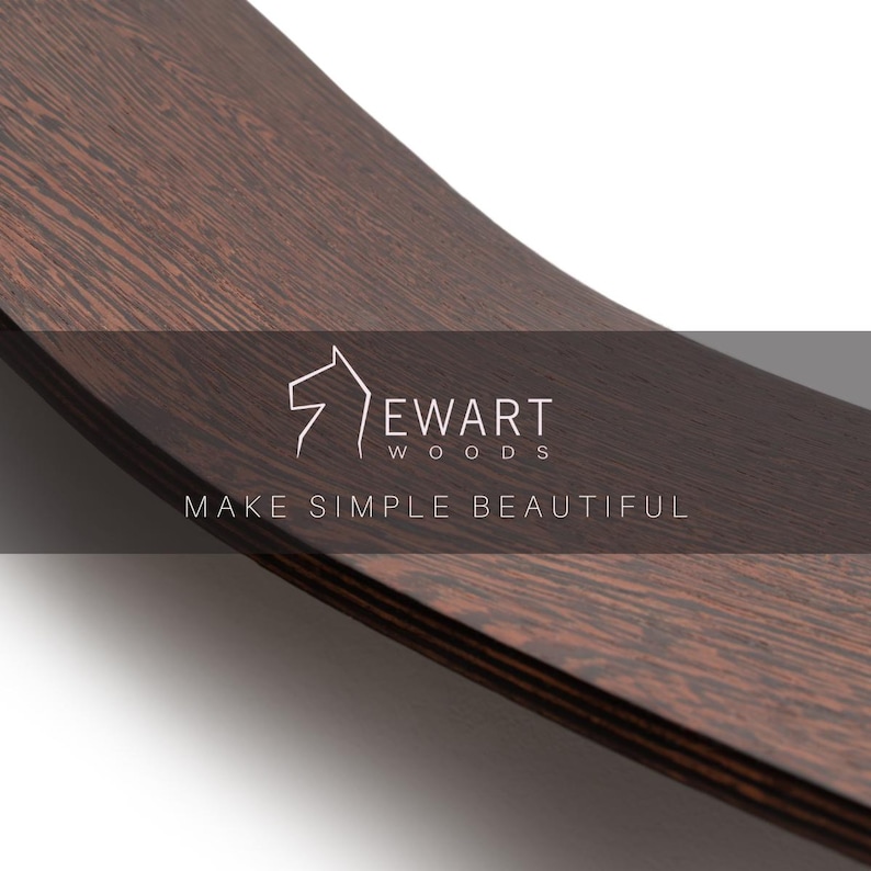 May include: Close-up of a curved, dark brown wooden surface with visible wood grain. The text "EWART WOODS" and "MAKE SIMPLE BEAUTIFUL" are displayed in white. The wood appears to be a rich, dark color.