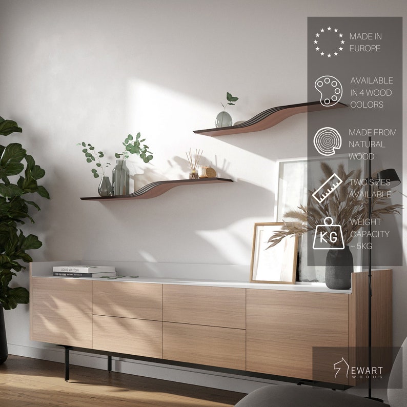 May include: Two modern, wavy wooden shelves in a living room setting. The shelves are a dark brown color with a layered design. The shelves are mounted on a white wall above a light wood cabinet. The image also shows decorative items on the shelves and cabinet. The text in the image says "MADE IN EUROPE", "AVAILABLE IN 4 WOOD COLORS", "MADE FROM NATURAL WOOD", "TWO SIZES AVAILABLE", and "WEIGHT CAPACITY ~5KG".
