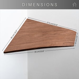 Op de afbeelding: Een driehoekig houten plankje, afmetingen: 35 cm lang, 26 cm breed en 9 cm diep. De plank is bruin en bevestigd aan een witte muur. Het woord "DIMENSIONS" staat bovenaan.