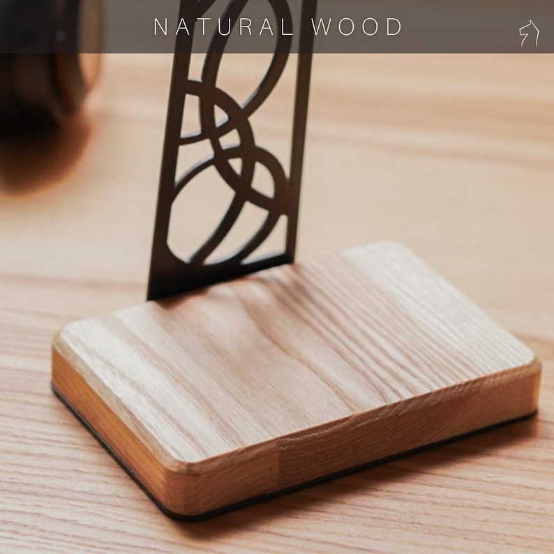 Close-up of a headphone stand's polished natural wood base, highlighting its smooth texture and wood grain. The sleek black steel frame contrasts the warm wood.
