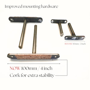 May include: Metal shelf brackets with cork for extra stability. The brackets are T-shaped with a rectangular base and a cylindrical support. The text reads "Improved mounting hardware" and "NOW 4 inch".