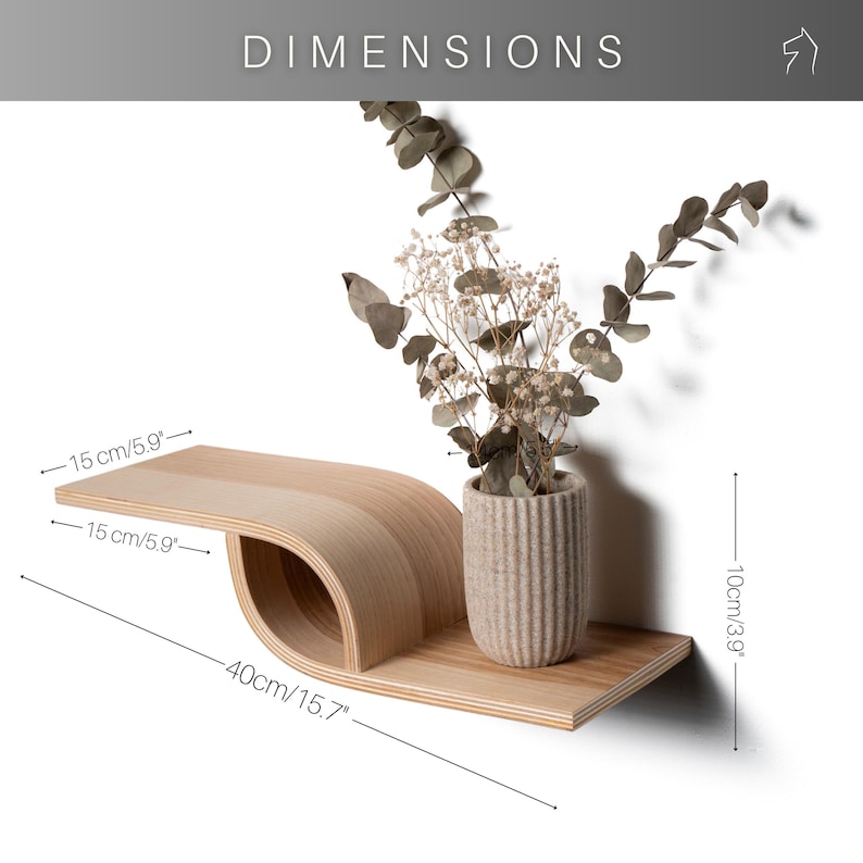 Pu&ograve; includere: Una mensola da parete in legno chiaro con un design curvo unico. La mensola &egrave; lunga 40 cm e alta 10 cm. Un piccolo vaso con fiori secchi &egrave; posto sulla mensola. La parola "DIMENSIONS" &egrave; in alto.