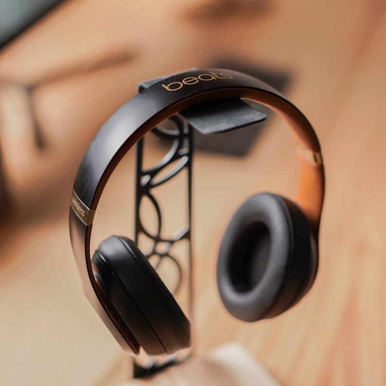 This sleek headphone stand features intricate circular cutouts in the steel frame, combining artistic flair with functionality.