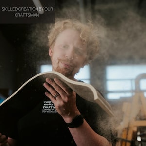 Pu&ograve; includere: Un artigiano lavora il legno, creando un pezzo curvo. L'immagine mostra l'artigiano con un pezzo di legno, con il testo "SKILLED CREATION BY OUR CRAFTSMAN" in alto. L'artigiano indossa una maglietta nera con testo bianco.