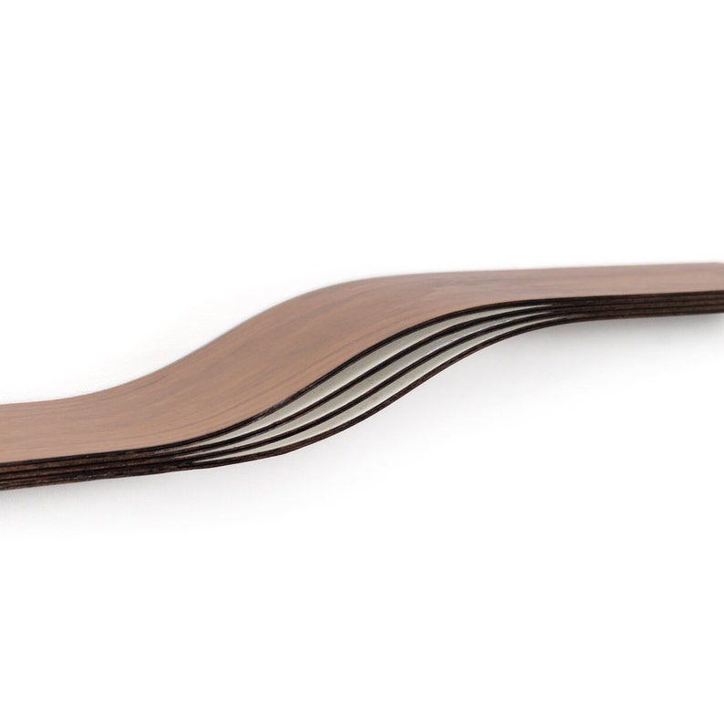 May include: A set of five curved wooden shelves with a dark brown finish. The shelves have a wavy design and are stacked on top of each other, creating a layered effect. The edges of the shelves are visible, showing the different layers of wood.