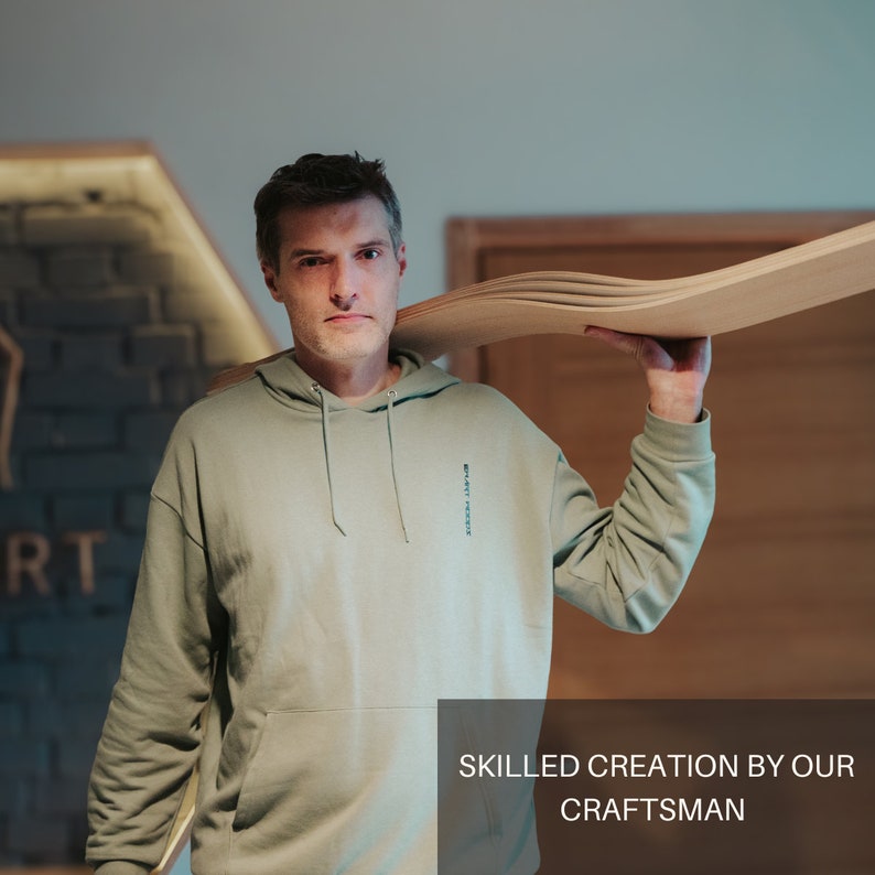 May include: A man wearing a light green hoodie holds several curved wooden boards over his shoulder. The boards are light brown. The text "SKILLED CREATION BY OUR CRAFTSMAN" is at the bottom of the image.