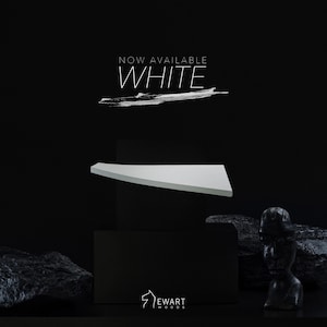 Op de afbeelding: Een witte, driehoekige plank wordt weergegeven tegen een zwarte achtergrond. De tekst "NOW AVAILABLE WHITE" staat boven de plank. Het Ewart Woods-logo staat onderaan. De plank lijkt van hout te zijn.