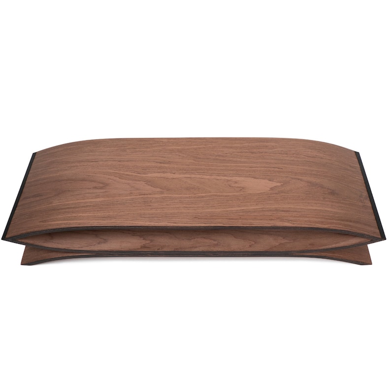 May include: A curved wooden stand with a rich brown walnut grain finish and dark edges. The object features a symmetrical, arched top and bottom piece that meet at the sides, creating a hollow, elongated oval opening through the center.