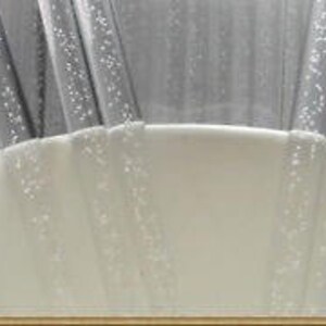 May include: Close-up of four clear plastic drinking straws with a textured surface. The straws are partially submerged in a white ceramic cup.