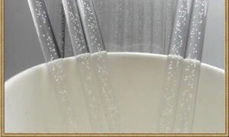 May include: Close-up of four clear plastic drinking straws with a textured surface. The straws are partially submerged in a white ceramic cup.