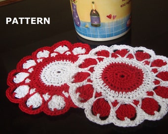 May include: Two handmade crochet coasters. Each coaster features a red center with a white, scalloped edge. The coasters are circular and are placed on a dark surface. The word "PATTERN" is in white text in the upper left corner.