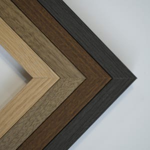 Puede incluir: Una colección de marcos de fotos de madera en varios tonos de marrón y gris, dispuestos en diagonal. Los marcos tienen un diseño simple y moderno y están hechos de madera.