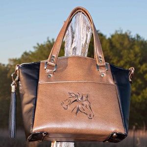 May include: A brown and black leather tote bag with a horse head design. The bag has a black tassel and gold hardware.