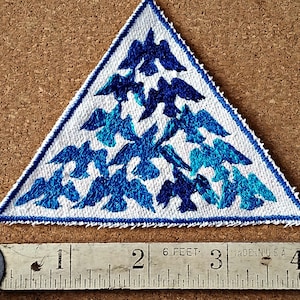 May include: Triangular patch with a white background and a border. The patch features a design of blue birds in various shades. The patch measures approximately 3 inches across at its widest point.