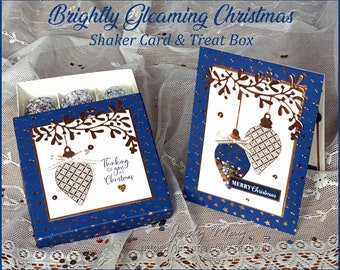May include: A blue and gold Christmas card and treat box set. The card features a gold glitter shaker ornament and the text "Merry Christmas". The box has a gold ornament design and the text "Thinking of you at Christmas".