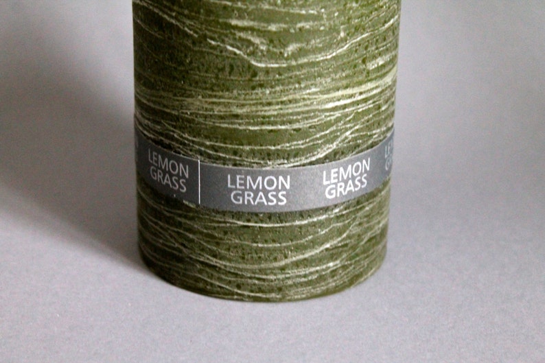 May include: A green pillar candle with a textured surface and a label that reads "LEMON GRASS".