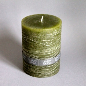 May include: A green pillar candle with a textured surface and the words "Lemon Grass" printed on the label.