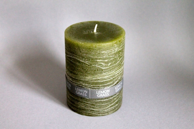 May include: A green pillar candle with a textured surface and the words "Lemon Grass" printed on the label.
