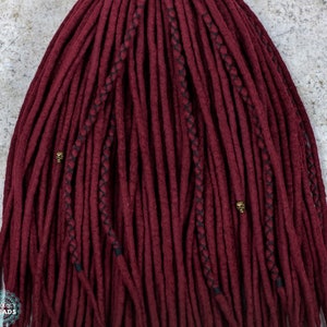 May include: Burgundy red synthetic dreadlocks with black stitching and gold skull beads.