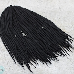 May include: A set of black synthetic dreadlocks with silver beads and a silver charm. The dreadlocks are arranged in a loose, flowing style.