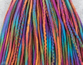 May include: Close-up of colorful dreadlocks in shades of purple, orange, blue, and green. Some dreads are accented with orange stitching or silver beads. The dreadlocks are arranged closely together, creating a vibrant and textured appearance.