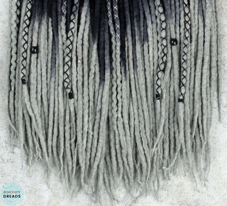 May include: Gray and black ombre synthetic dreadlocks with silver and black beads. The dreadlocks are approximately 24 inches long.