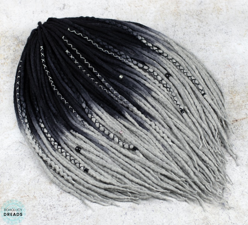 May include: Black and gray ombre synthetic dreadlocks with silver beads. The dreadlocks are tied together at the top.