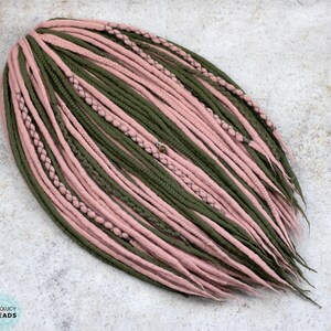 May include: A set of synthetic dreadlocks in shades of pink and green. The dreadlocks are arranged in a fan shape and are ready to be added to hair.