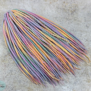 May include: A set of colorful wool dreadlocks in shades of pink, purple, yellow, and green. The dreadlocks are tied together at the top and have a braided design.
