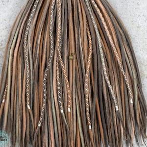 May include: A set of brown, tan, and gray wool dreadlocks with white stitching. The dreadlocks are tied together at the top.