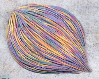 May include: A bundle of colorful synthetic dreadlocks in shades of yellow, purple, blue, and green. The dreadlocks are tied together at the top and have a white string woven through them.