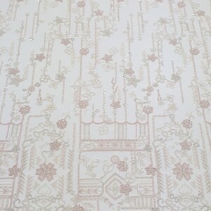 May include: White beaded fabric with a pink floral pattern. The fabric has a geometric design with small flowers and leaves.