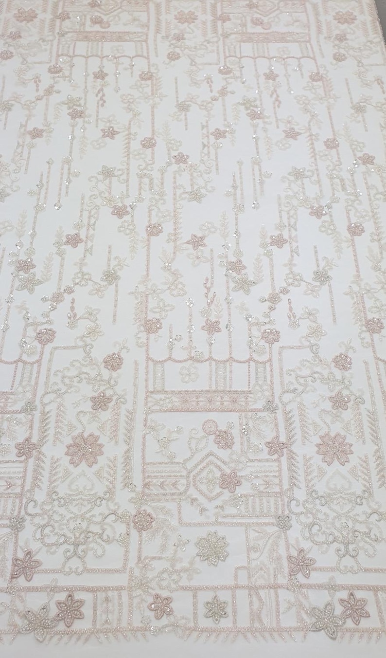 May include: White beaded fabric with a pink floral pattern. The fabric has a geometric design with small flowers and leaves.