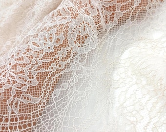 Puede incluir: Primer plano de una delicada tela de encaje marfil. Los intrincados patrones florales y geométricos crean una superficie texturizada. El encaje se utiliza probablemente para vestidos de novia, vestidos u otras prendas elegantes.