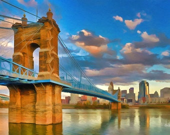 Può includere: Un ponte sospeso blu con una torre in pietra marrone, che attraversa un fiume con uno skyline cittadino sullo sfondo. Il cielo è blu con nuvole bianche.