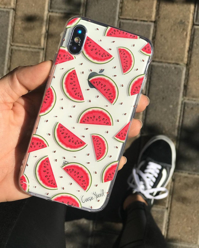 Pu&ograve; includere: Una custodia per telefono trasparente con sfondo bianco e un motivo ripetuto di fette di anguria rosse. La custodia ha il testo "Case Yard" stampato nell'angolo in basso a destra.
