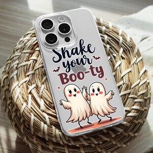 Op de afbeelding: Een transparante telefoonhoes met een grijze achtergrond en een ontwerp van twee geesten met de tekst "Shake your Boo-ty" in zwarte en rode letters.