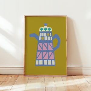 May include: A framed art print depicting a stylized coffee pot. The design uses blue, pink, and white against a mustard yellow backdrop. The artwork is displayed on a wooden floor.