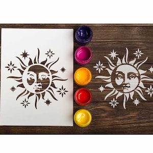 以下が含まれることがあります： 太陽と星をデザインした白いステンシル。太陽は顔があり、光線に囲まれています。星は五芒星で、太陽の周りに散らばっています。