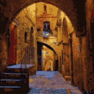 May include: A narrow, arched passageway in a stone building with a warm, golden light shining through. The walls are textured and the floor is cobblestone.