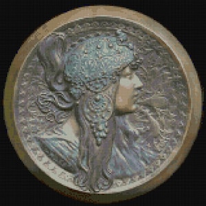 May include: A circular, bronze-colored metal medallion with a raised image of a woman's head in profile. The woman is wearing a crown of leaves and her hair is flowing down her back. The medallion has a textured surface and a raised rim.